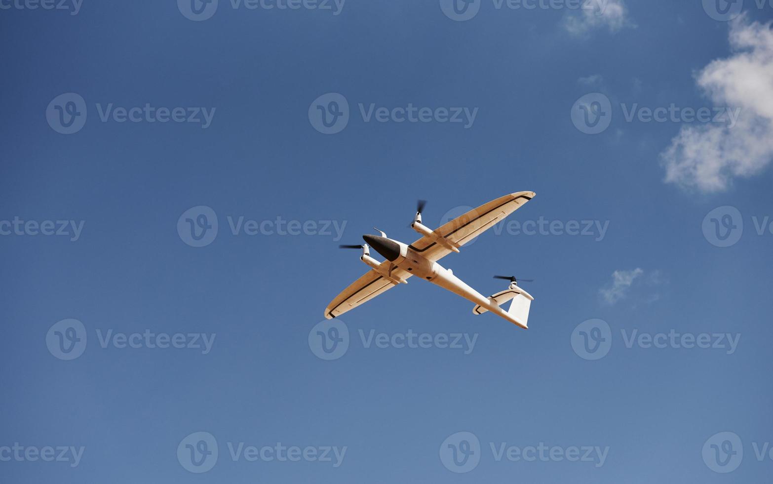 Modern small remote controlled white colored plane flying up in the sky photo