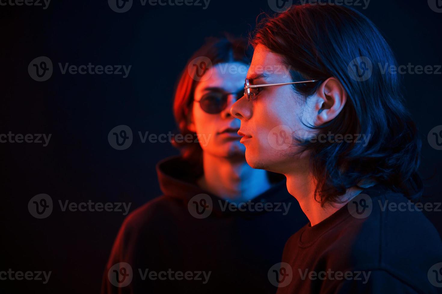 Colorful photo. Portrait of twin brothers. Studio shot in dark studio with neon light photo