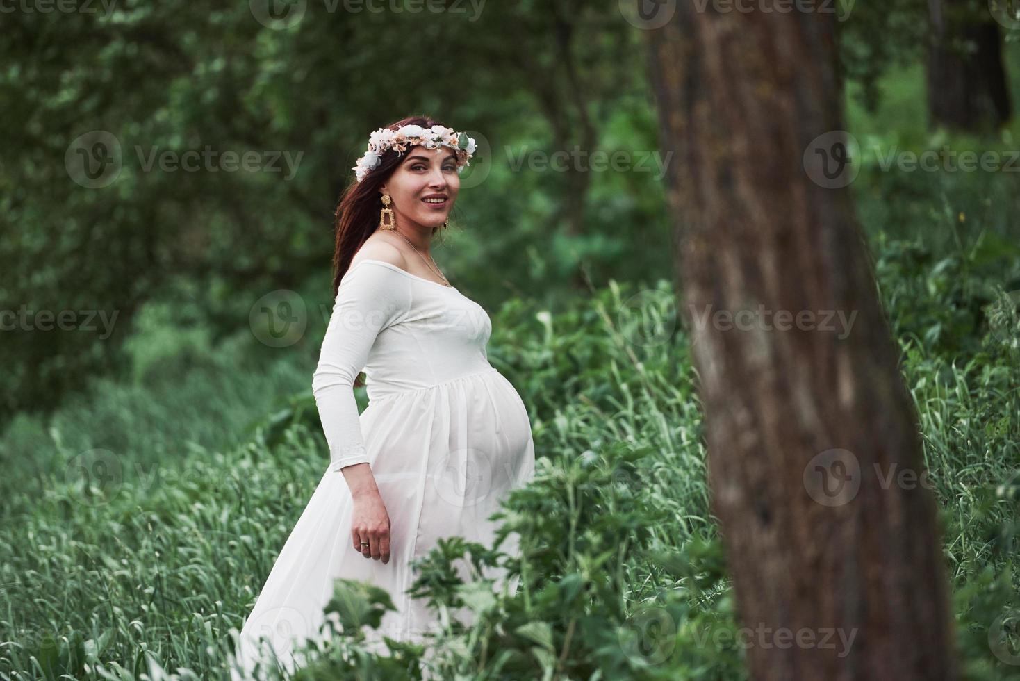 Good morning. Beautiful pregnant woman in dress have a walk outdoors. Positive brunette photo