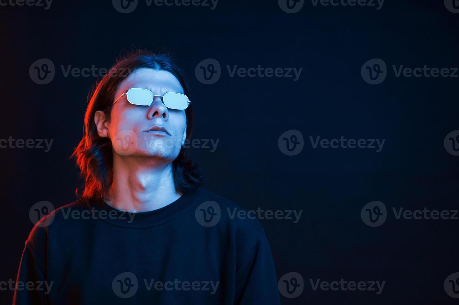 mirando lejos foto de estudio en estudio oscuro con luz de neón. retrato de hombre serio