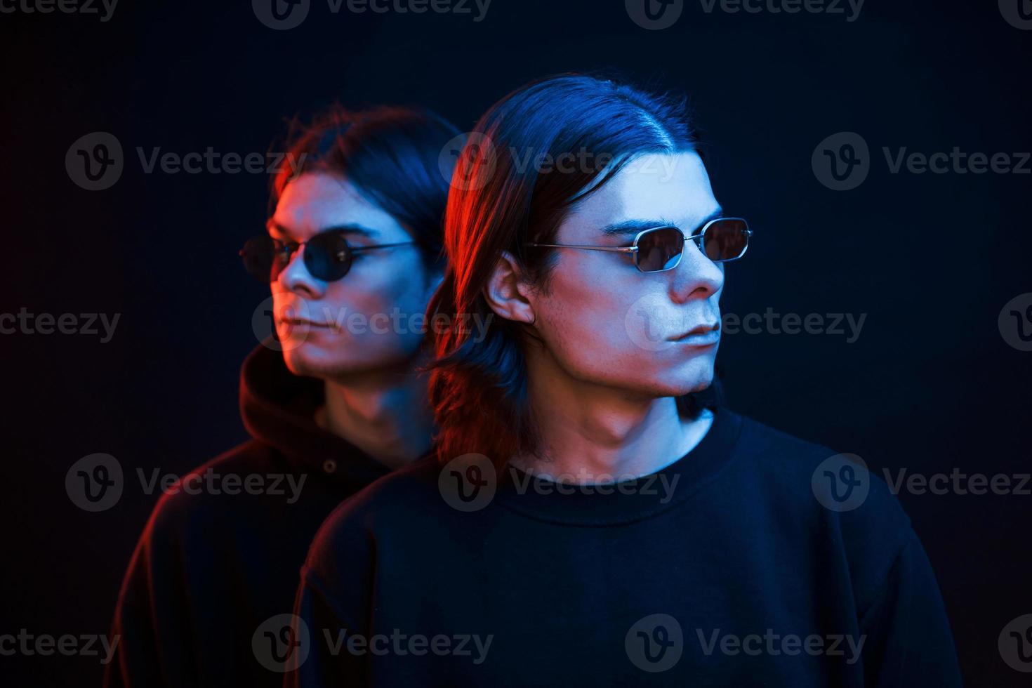 juntos estamos. retrato de hermanos gemelos. foto de estudio en estudio oscuro con luz de neón