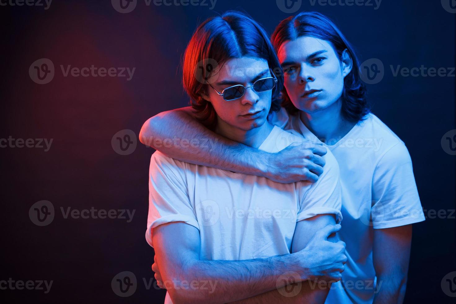 Family is very important. Portrait of twin brothers. Studio shot in dark studio with neon light photo