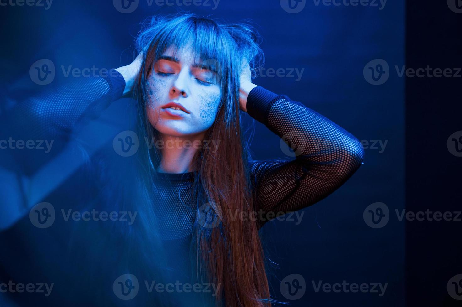 Gorgeous person. Studio shot in dark studio with neon light. Portrait of young girl photo