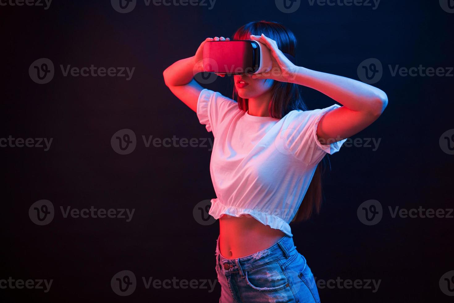 mujer joven que usa gafas de realidad virtual en la habitación oscura con luces de neón foto