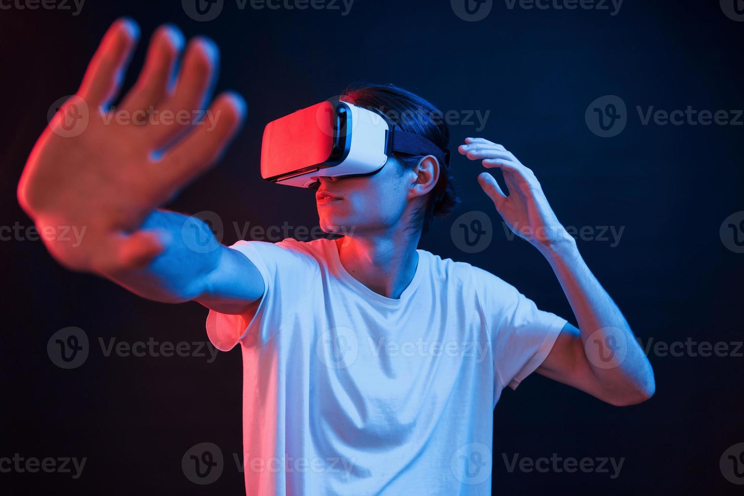 una especie de juego de arcade. joven usando gafas de realidad virtual en la habitación oscura con luces de neón foto