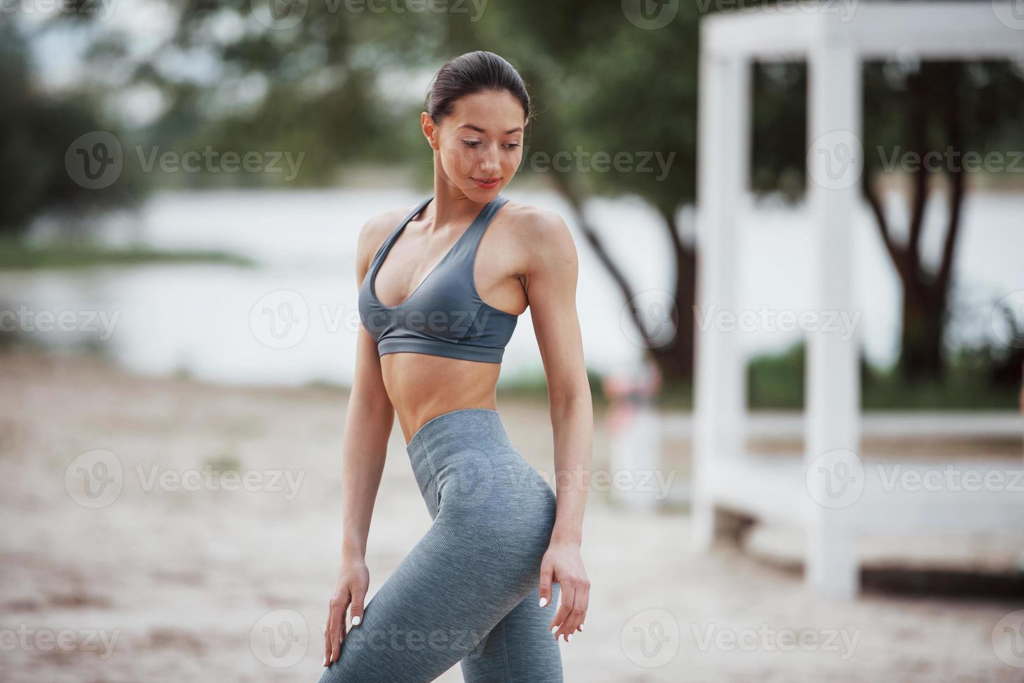 Alone in the park. Brunette with nice body shape in sportive clothes have fitness day on a beach photo