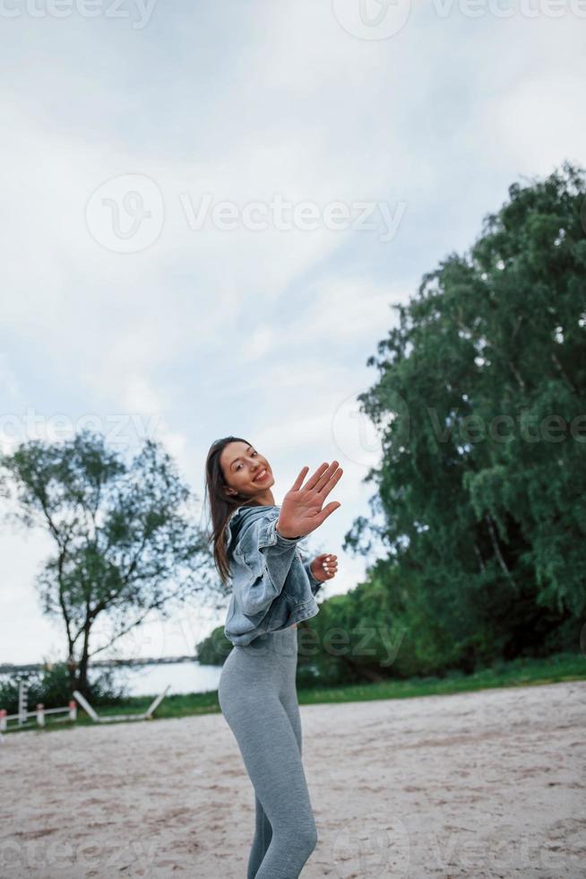 Te veo pronto. mujer positiva con ropa deportiva disfrutando de la naturaleza en la playa foto