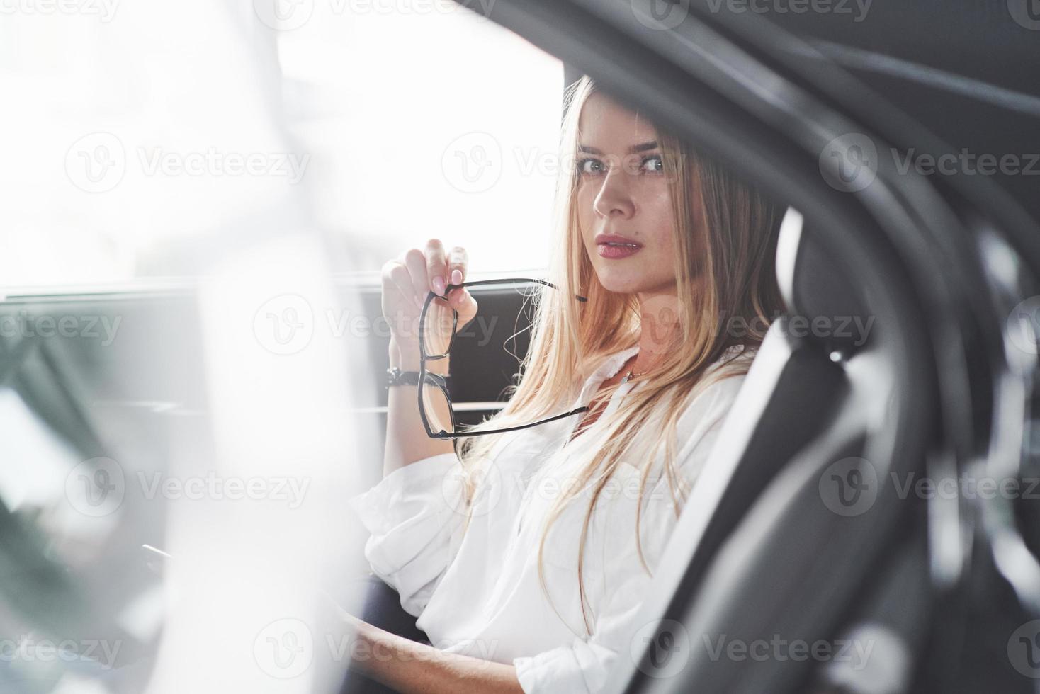 Some bad news. Beautiful blonde girl sitting in the new car with modern black interior photo