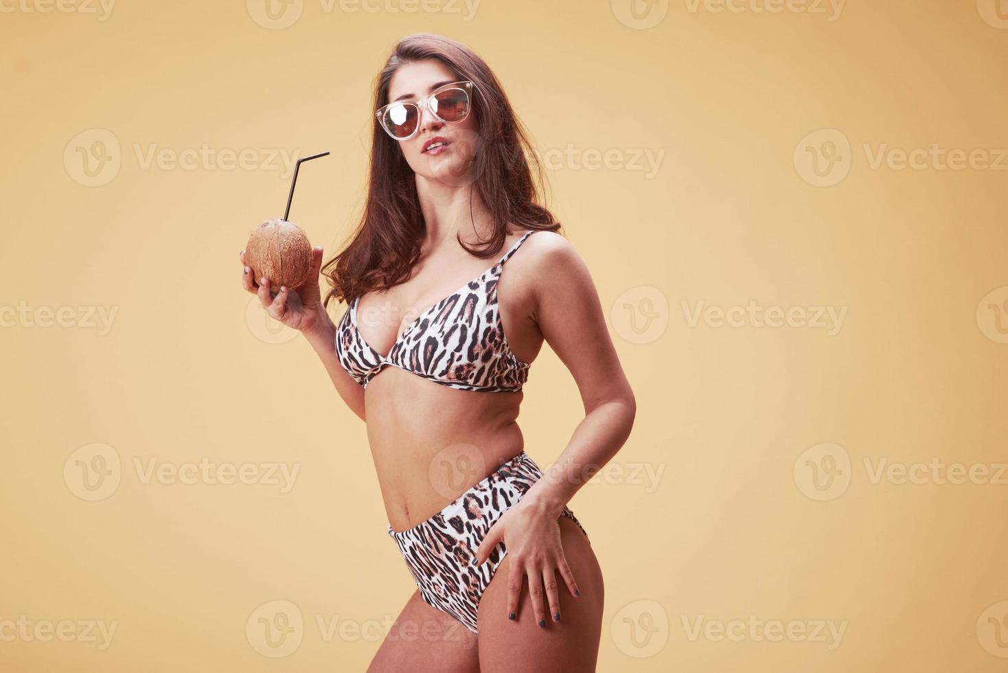 Estoy listo para la luz del sol de la playa. hermosa joven con estilo en soportes de bikini y posando en el estudio foto