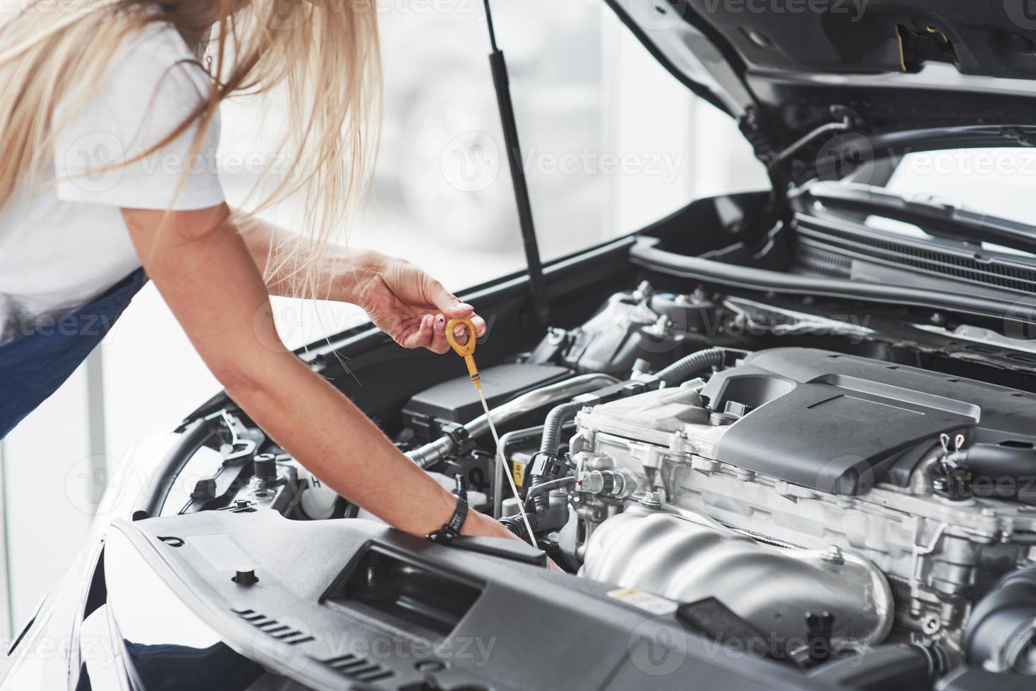 Give me a little more time. Car addicted woman repairs black car indoors in garage at daytime photo