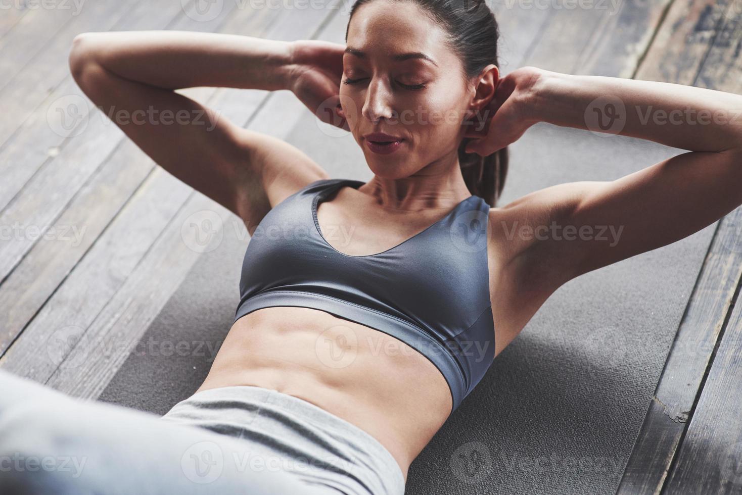 No pain, no results. Girl with slender body works on the abs when lying on the floor photo