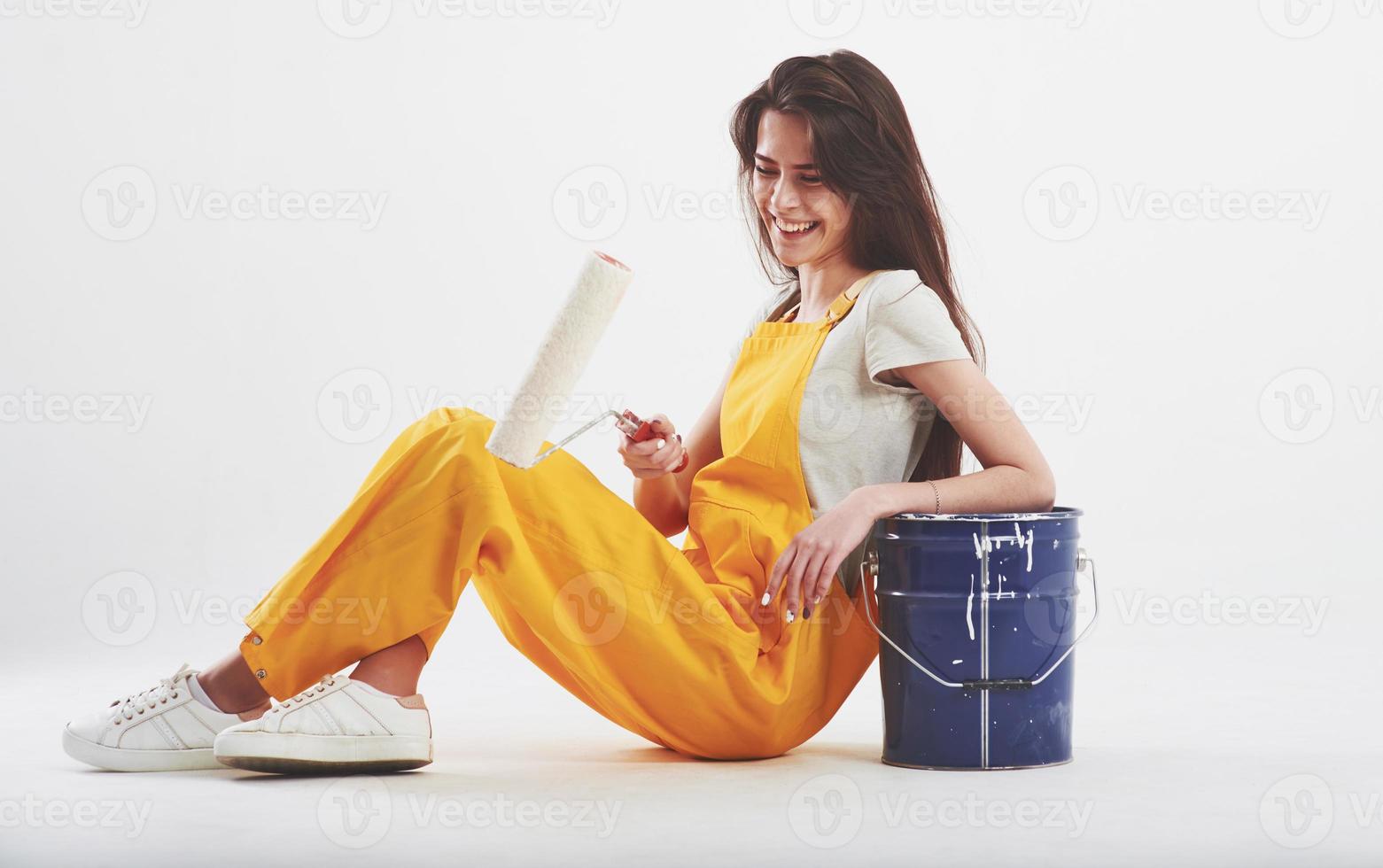 Easy and fun. Brunette woman in yellow uniform sits against white background in the studio photo