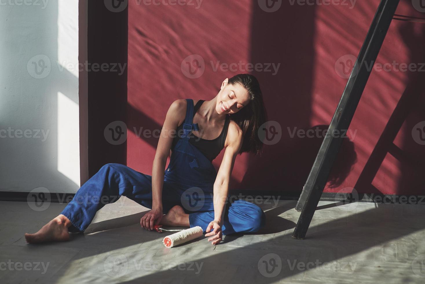 I'm done, I can relax now. Young housewife decided to glue wallpaper in her new house in the room photo