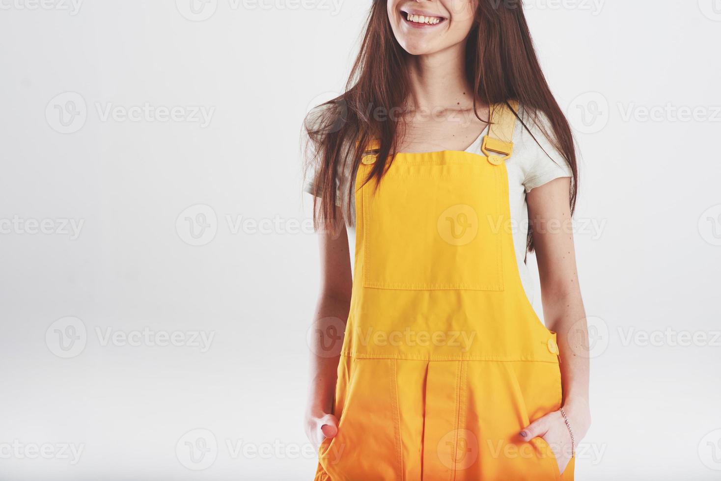 Smiling for the camera. Brunette woman in yellow uniform stands against white background in the studio photo