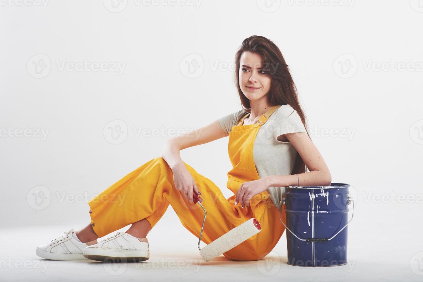 Designer occupation. Brunette woman in yellow uniform sits against white background in the studio photo