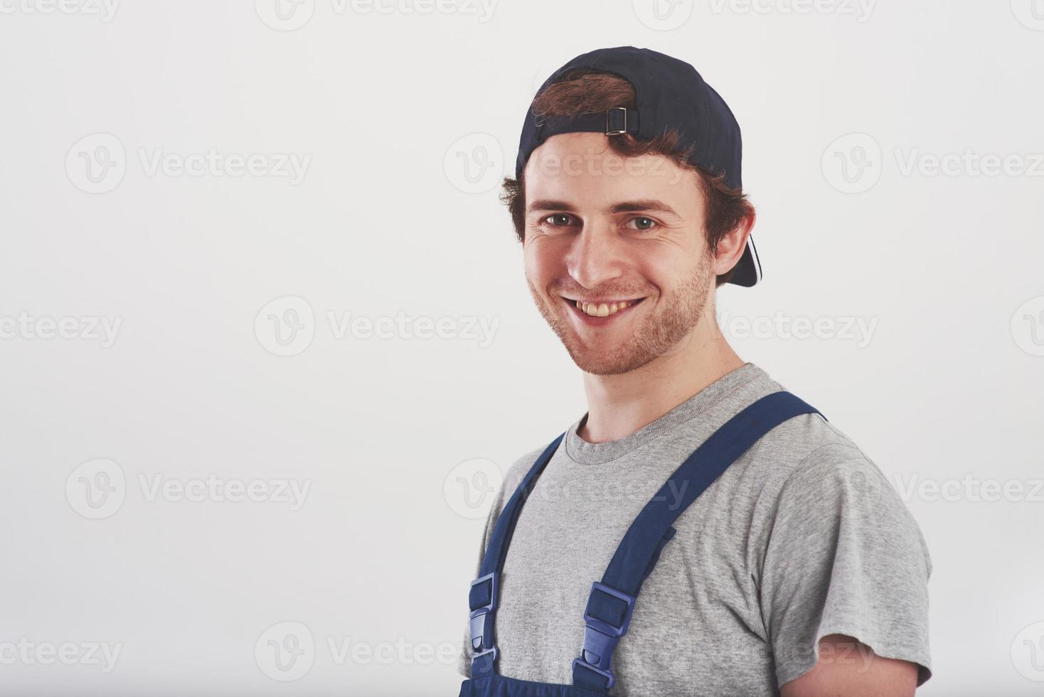 Positive customer happy to see you. Man in blue uniform stands against white background in the studio photo