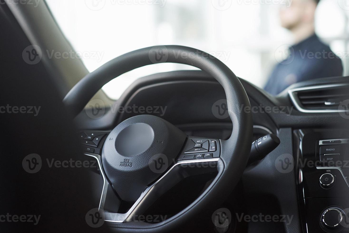 dentro de un auto negro nuevo. interiores de lujo. el hombre se para frente al automóvil foto