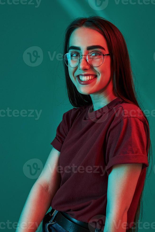 Having good mood. Studio shot indoors with neon light. Portrait of beautiful young girl photo