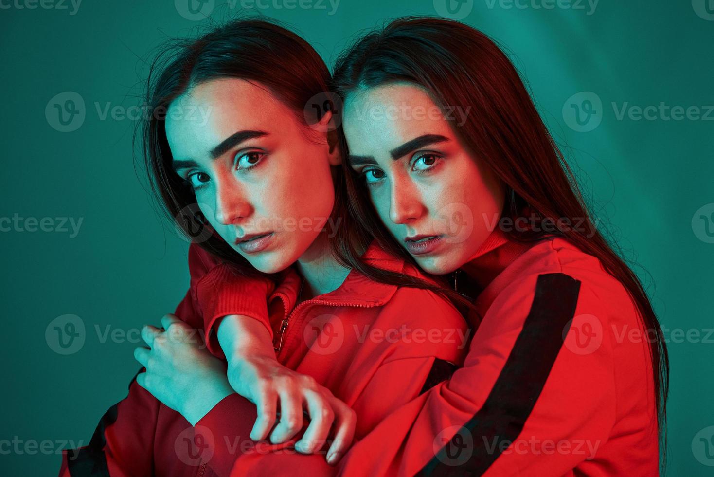 Calm and quiet. Studio shot indoors with neon light. Photo of two beautiful twins