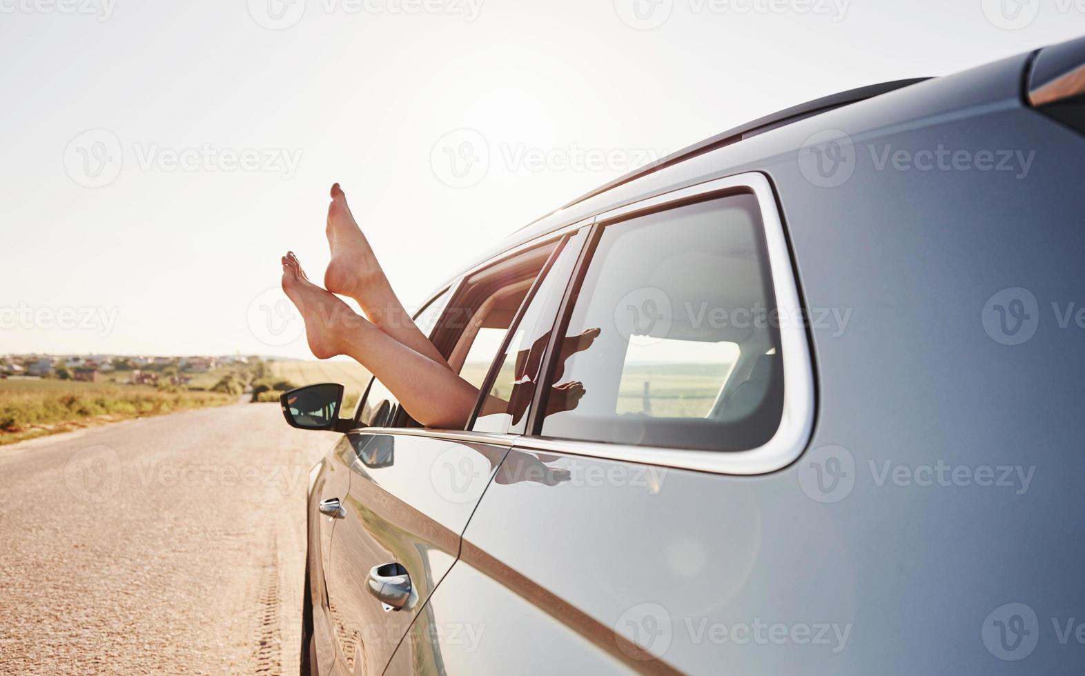 en la carretera. chica pone sus piernas en la ventana del automóvil en el campo foto