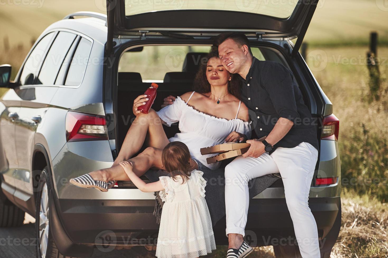 Parents sits on the back of automobile. Beautiful people is in the modern car at their weekends photo