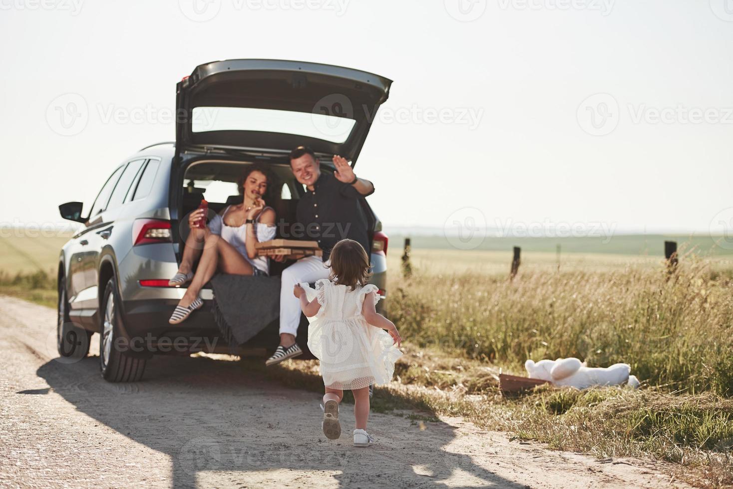 Mother and fathes eating pizza. Beautiful people is in the modern car at their weekends photo