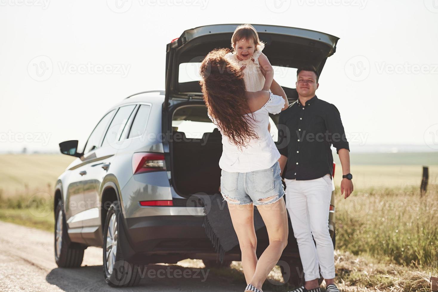 Family have some good time at countryside near silver automobile at sunset photo