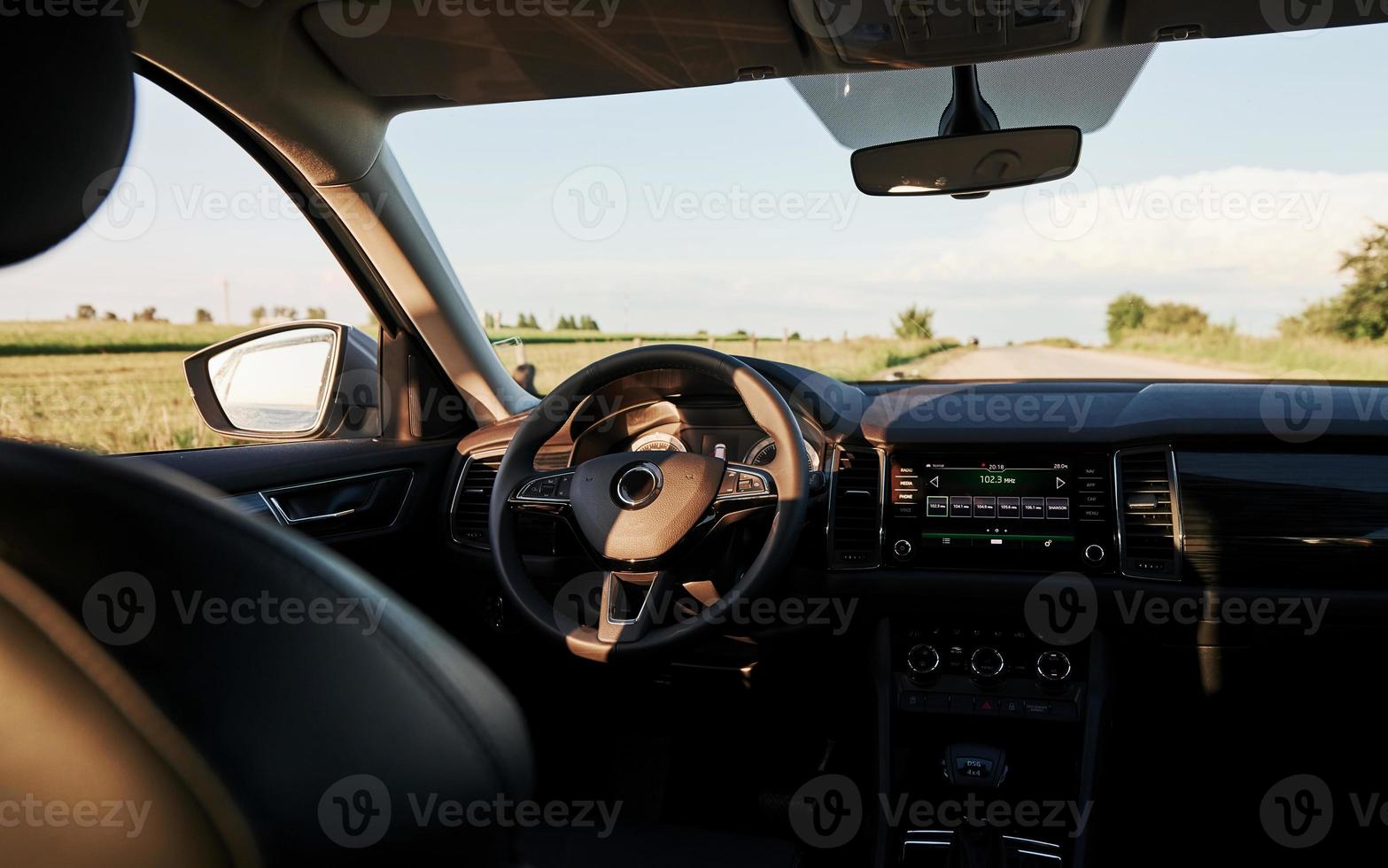 At countryside. Inside modern car. Front panel, steering wheel, quality material photo