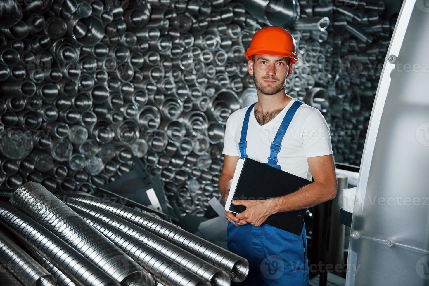 In orange colored safety helmet. Man in uniform works on the production. Industrial modern technology photo