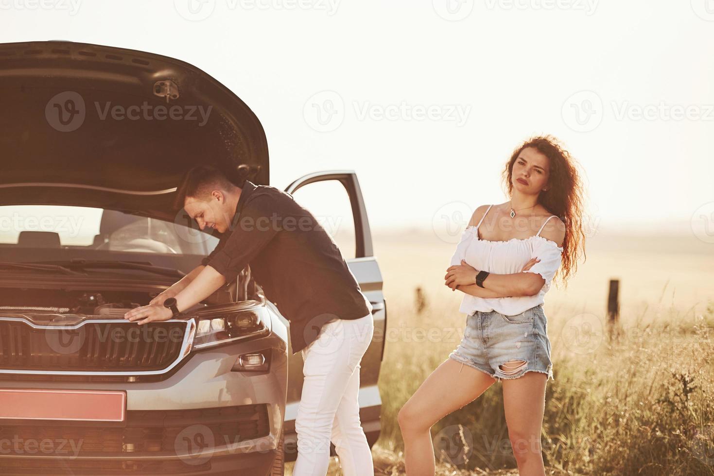 Man repairs car of girl with curly hair. Mechanical assistance photo