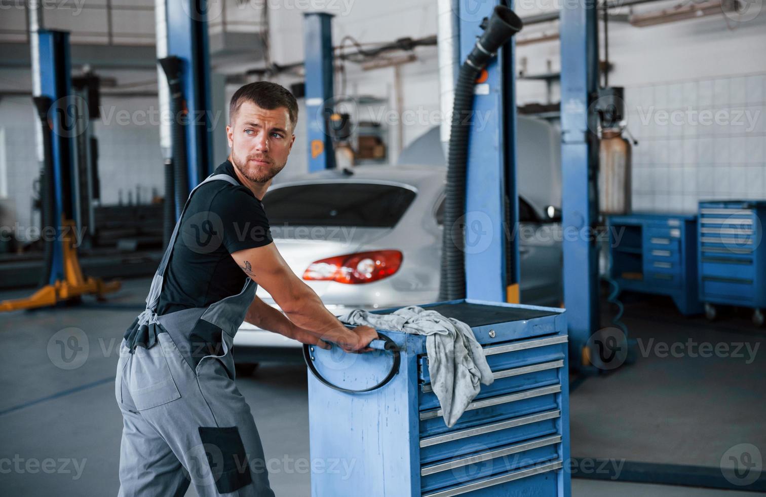 One person only. Male mechanic use different tools to repair broken automobile in garage photo