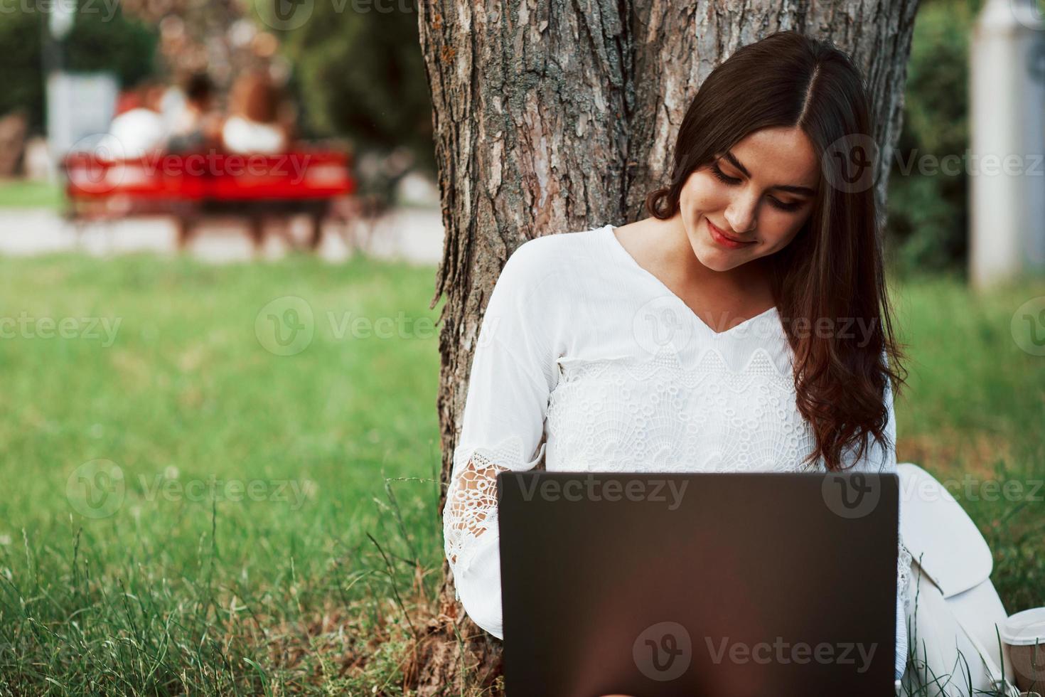 Using internet. Young woman have weekend and sits in the park at daytime photo