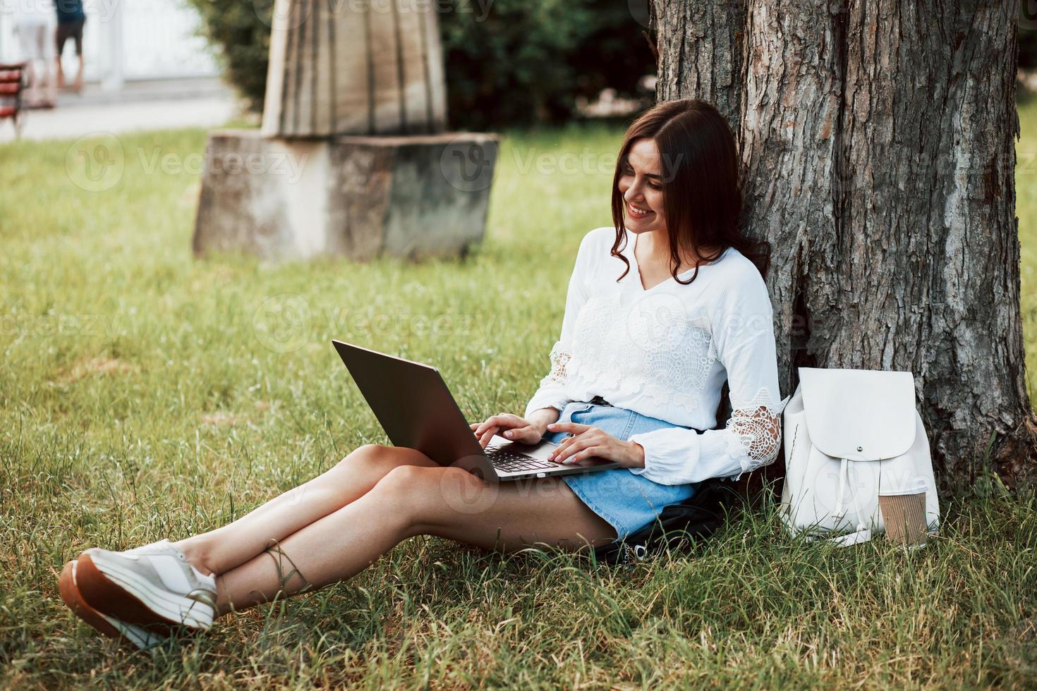 Time to rest. Young woman have weekend and sits in the park at daytime photo