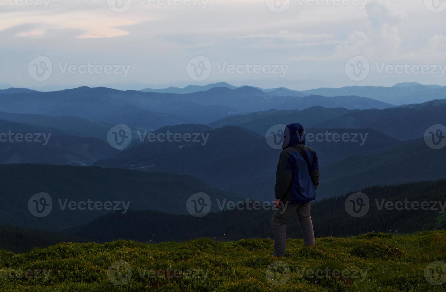 Man stands on the hill and looks far away. Majestic Carpathian mountains. Beautiful landscape. Breathtaking view photo