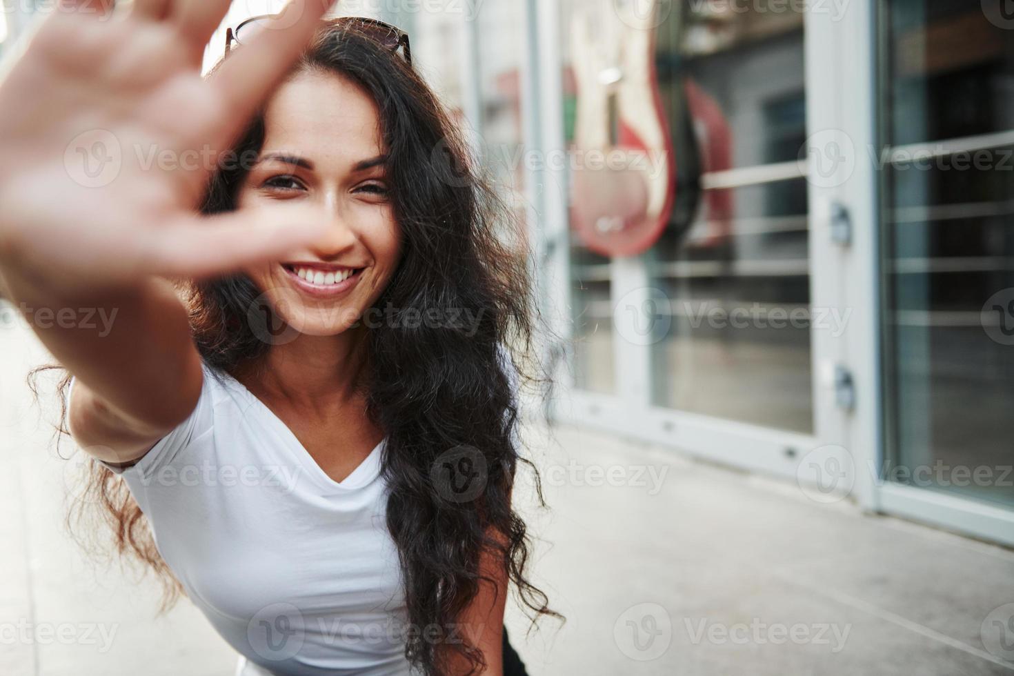 hermosa mujer con cabello negro rizado pasar un buen rato en la ciudad durante el día foto