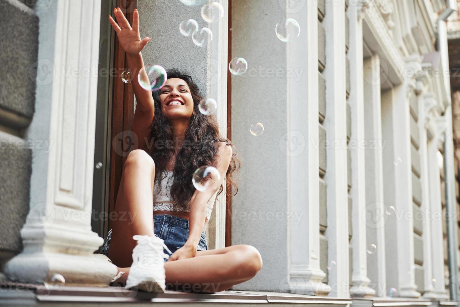 Old but nice building. Beautiful woman with curly black hair have good time in the city at daytime photo