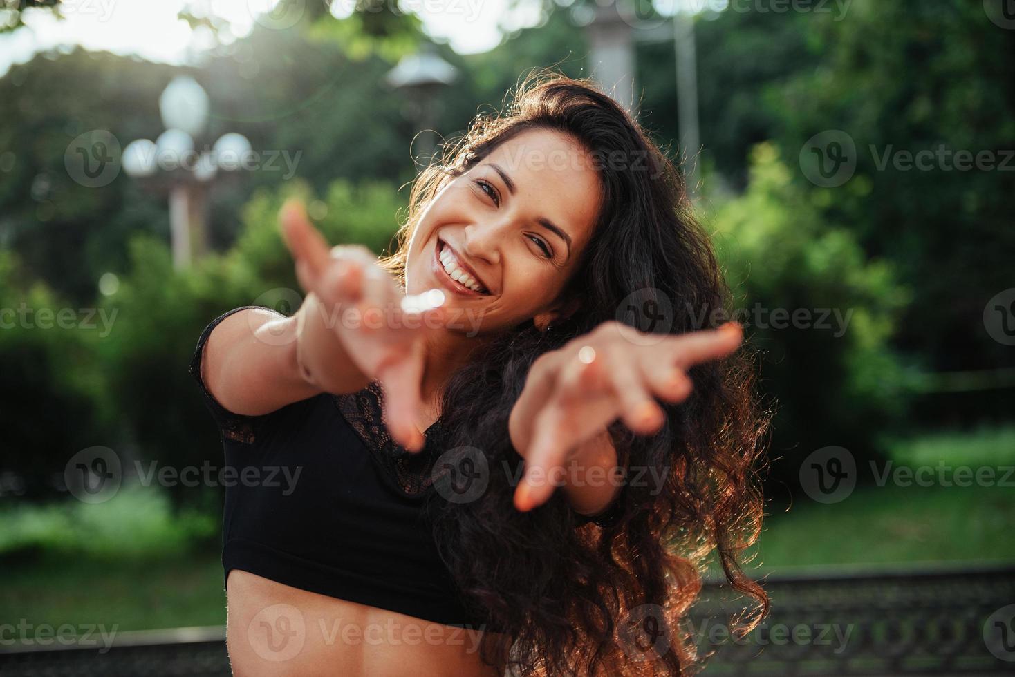 llena de energía vital. hermosa mujer con cabello negro rizado pasar un buen rato en la ciudad durante el día foto