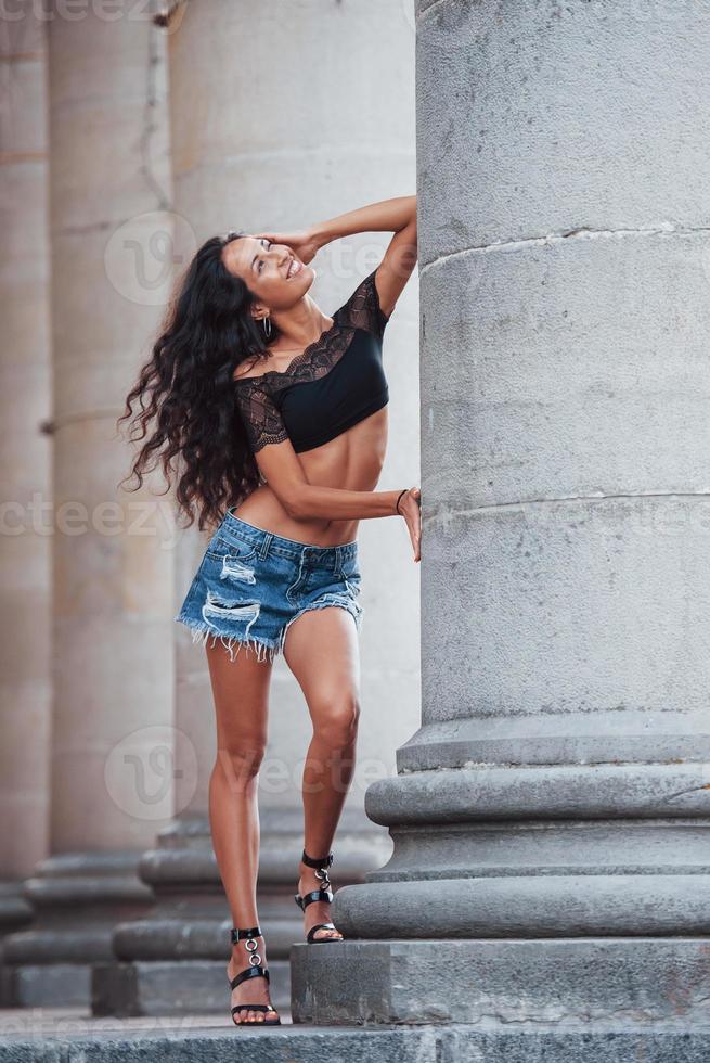 In shorts. Beautiful woman with curly black hair have good time in the city at daytime photo