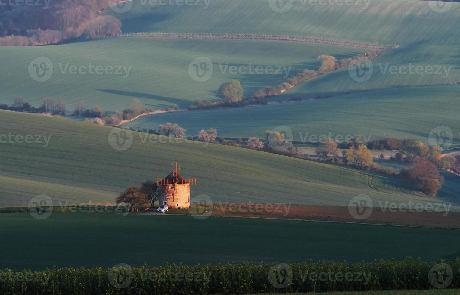 majestuoso paisaje de campo por la noche. molino de viento en el centro del prado foto