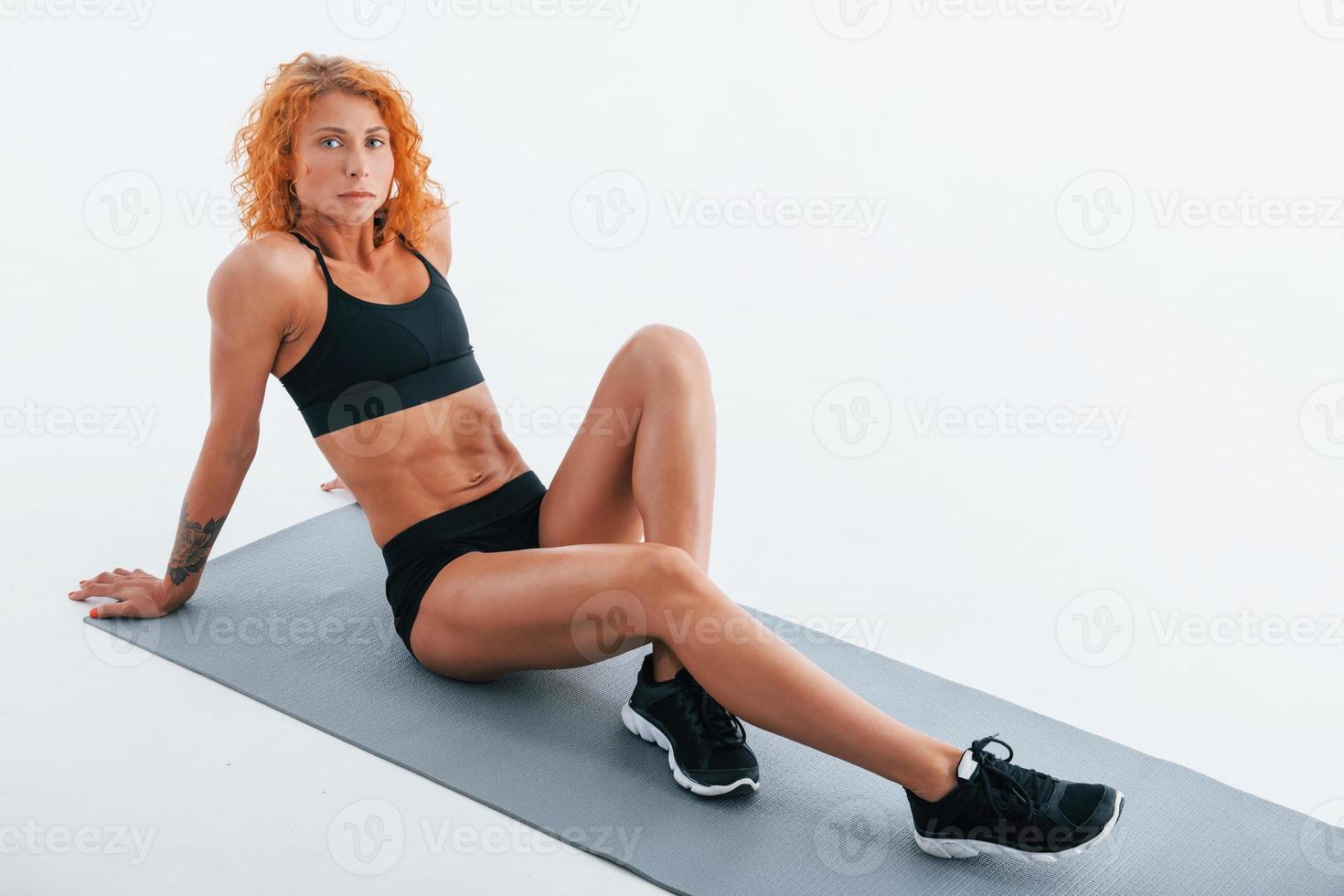 Rests on the roll mat. Redhead female bodybuilder is in the studio on white background photo