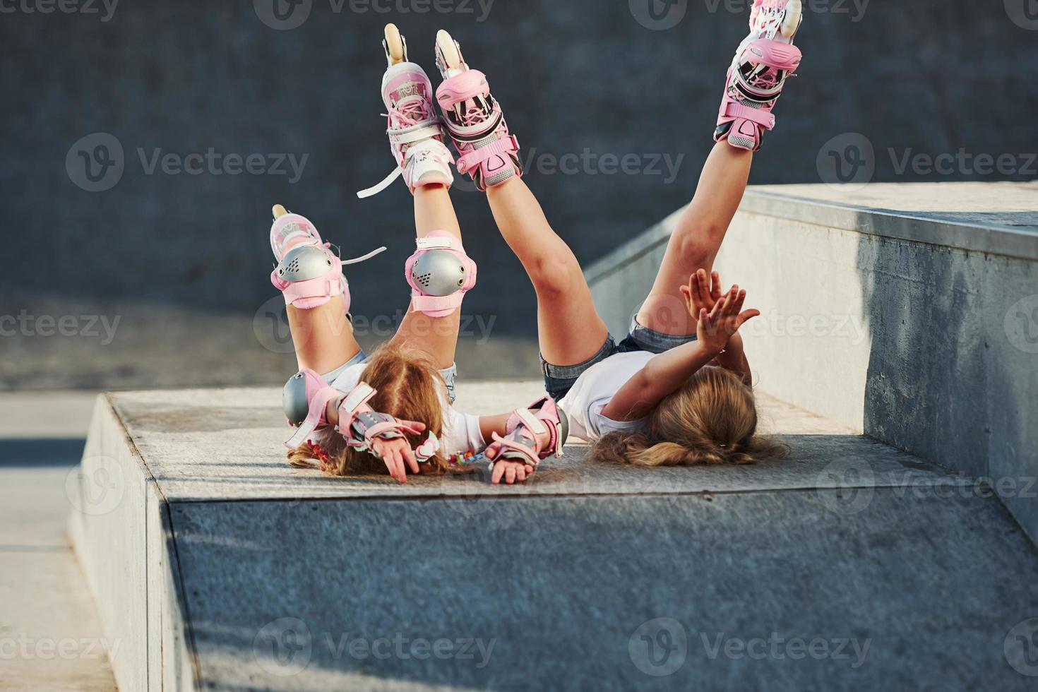 Legs up. Feeling free. On the ramp for extreme sports. Two little girls with roller skates outdoors have fun photo