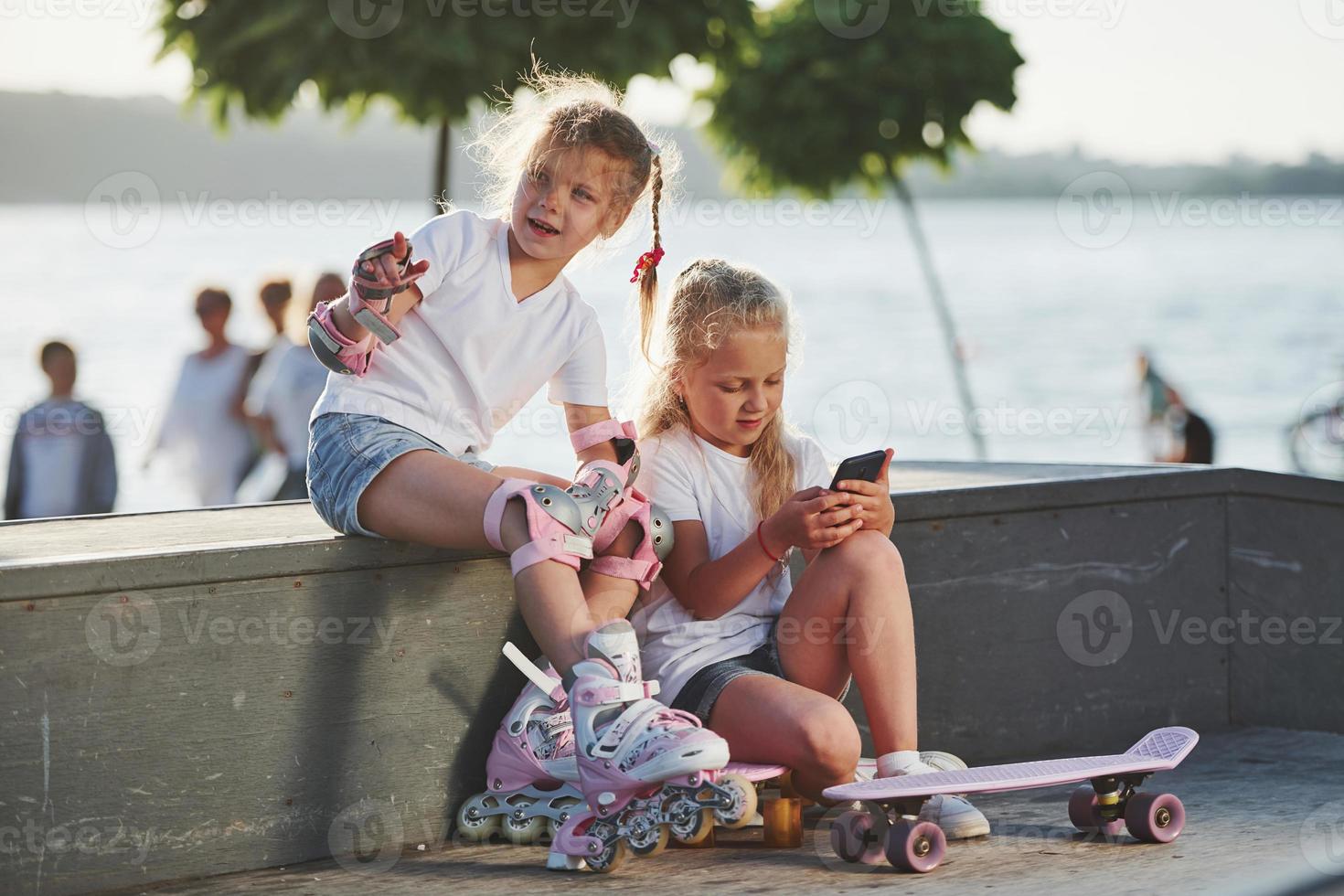 Talking with each other. On the ramp for extreme sports. Two little girls with roller skates outdoors have fun photo