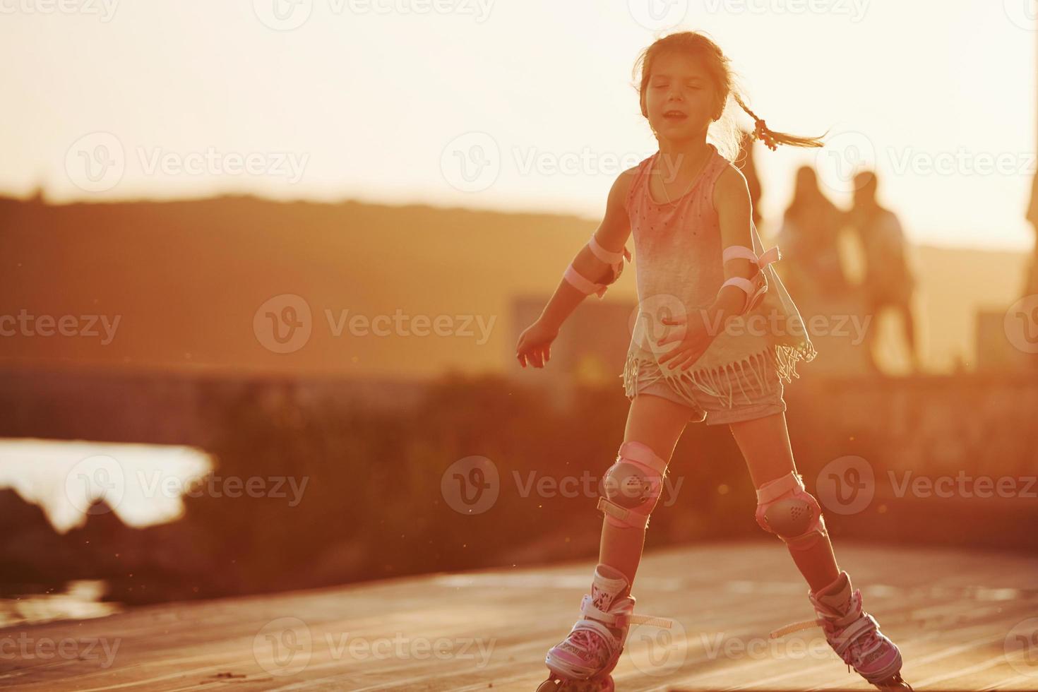 niño lindo feliz montando en sus patines. increíble luz del sol foto