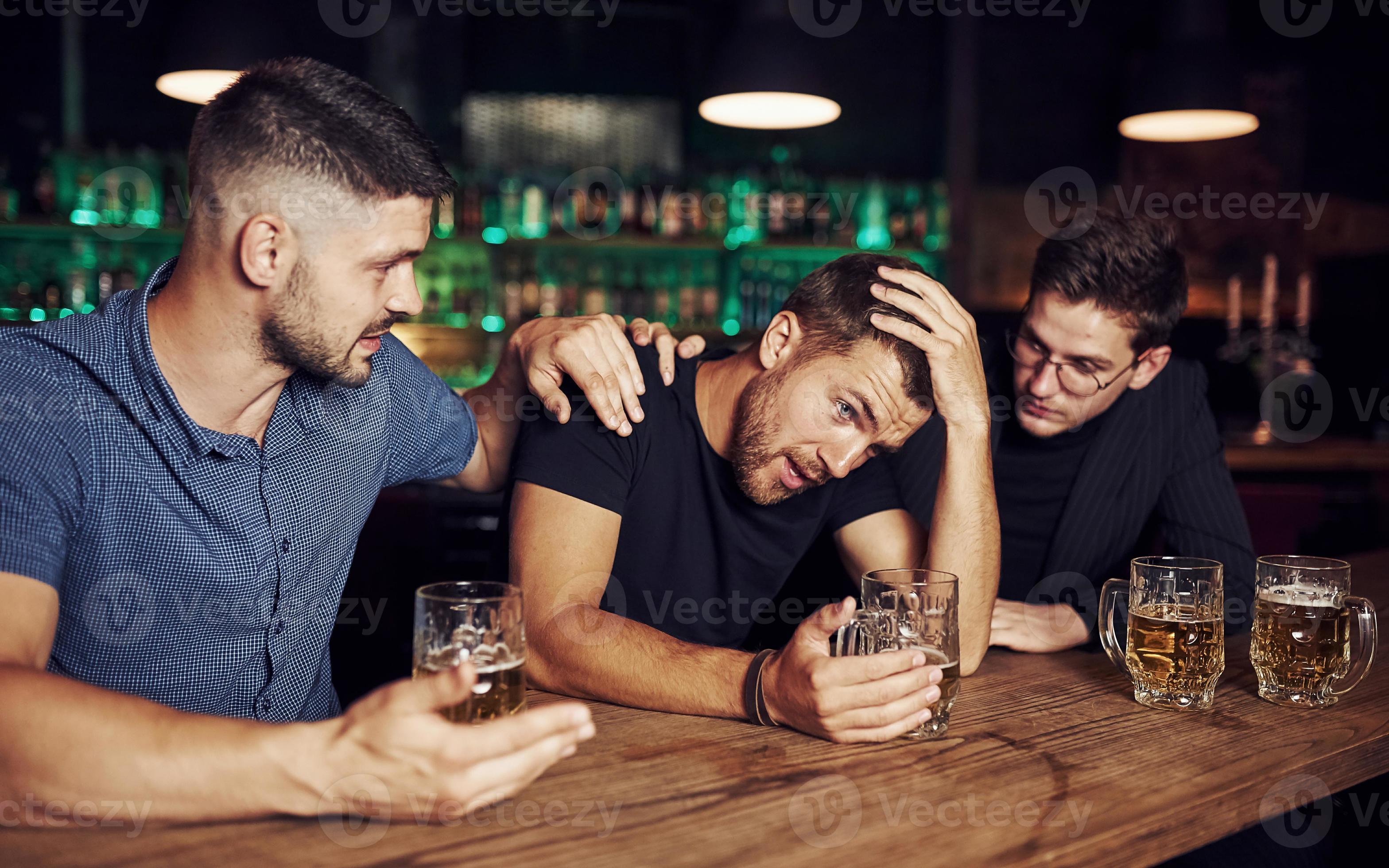 Three male friends in the bar. Supporting sad friend. Unity of people