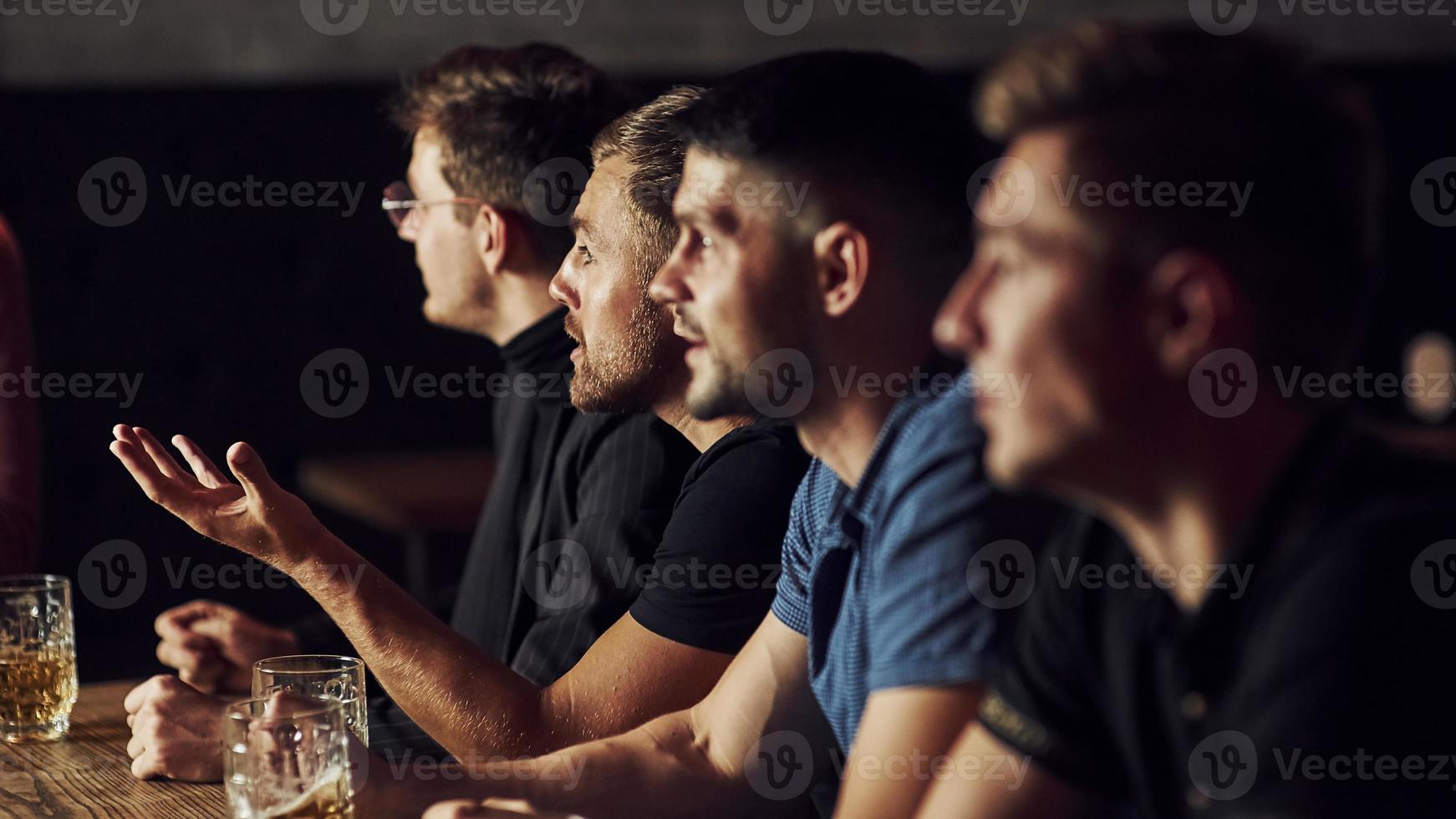 tres aficionados al deporte en un bar viendo fútbol. con cerveza en las manos foto