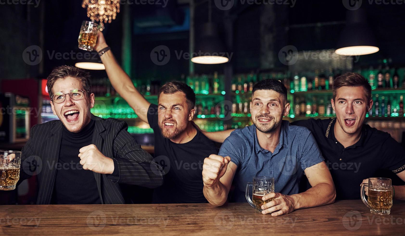 It's a goal. Celebrating victory. Three sports fans in a bar watching soccer. With beer in hands photo