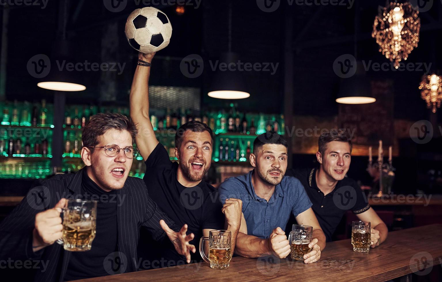 con balón de fútbol. es una meta celebrando la victoria. tres fanáticos de los deportes en un bar viendo fútbol con cerveza en las manos foto