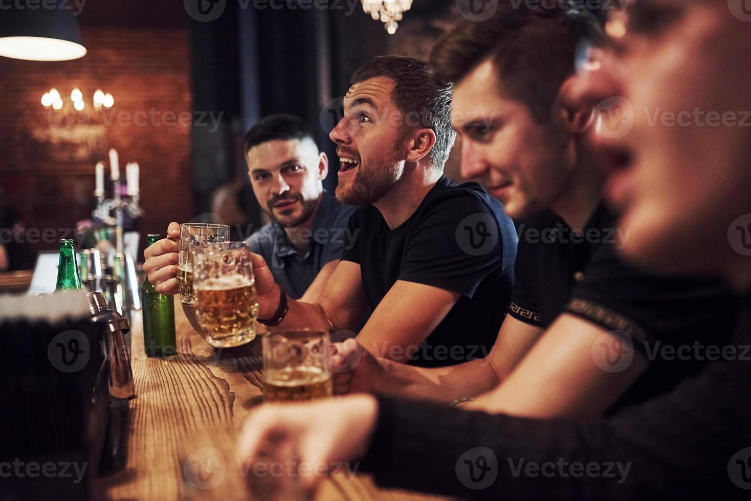 Positive people. Friends resting in the pub with beer in hands. Having conversation photo