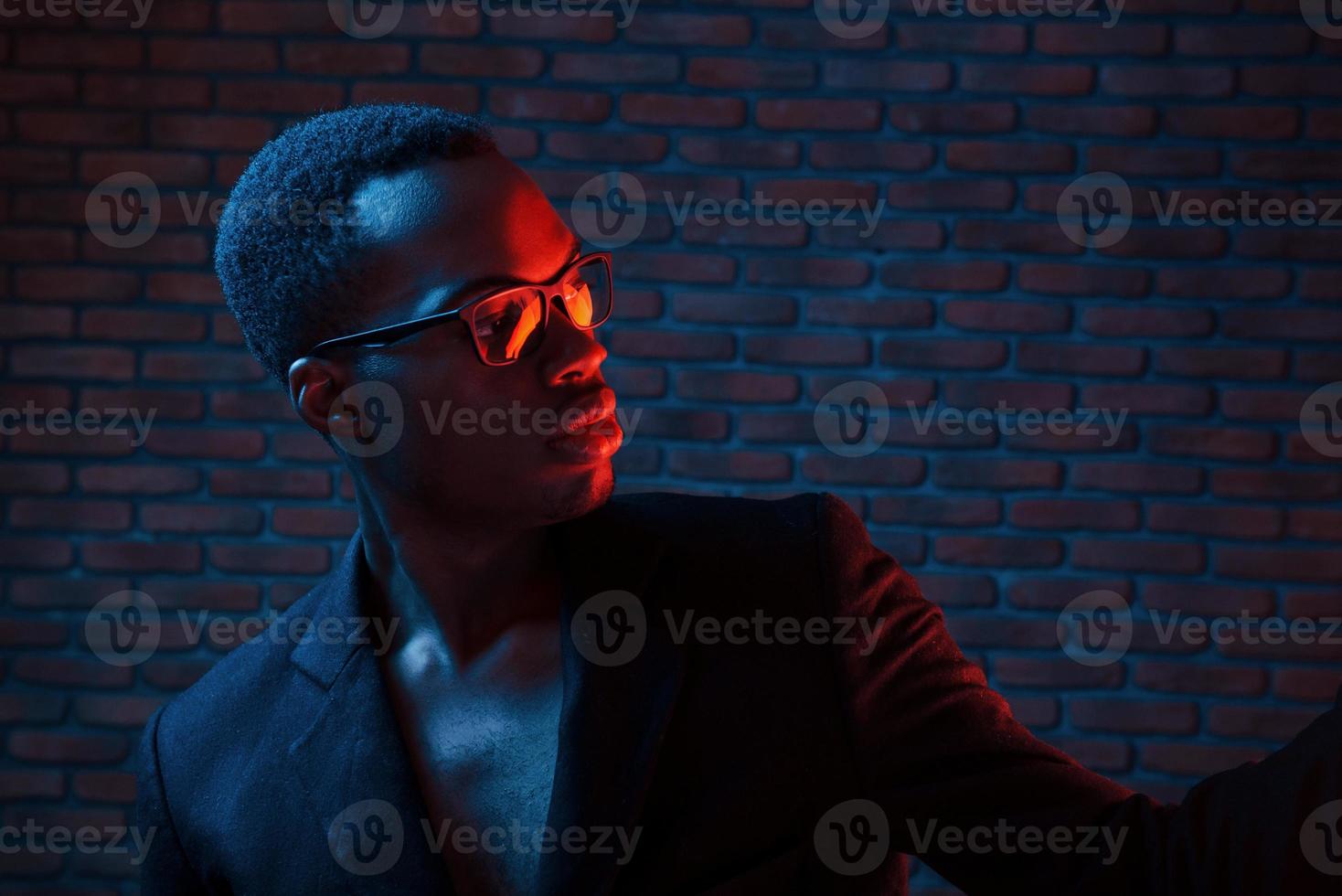 In eyewear. Futuristic neon lighting. Young african american man in the studio photo