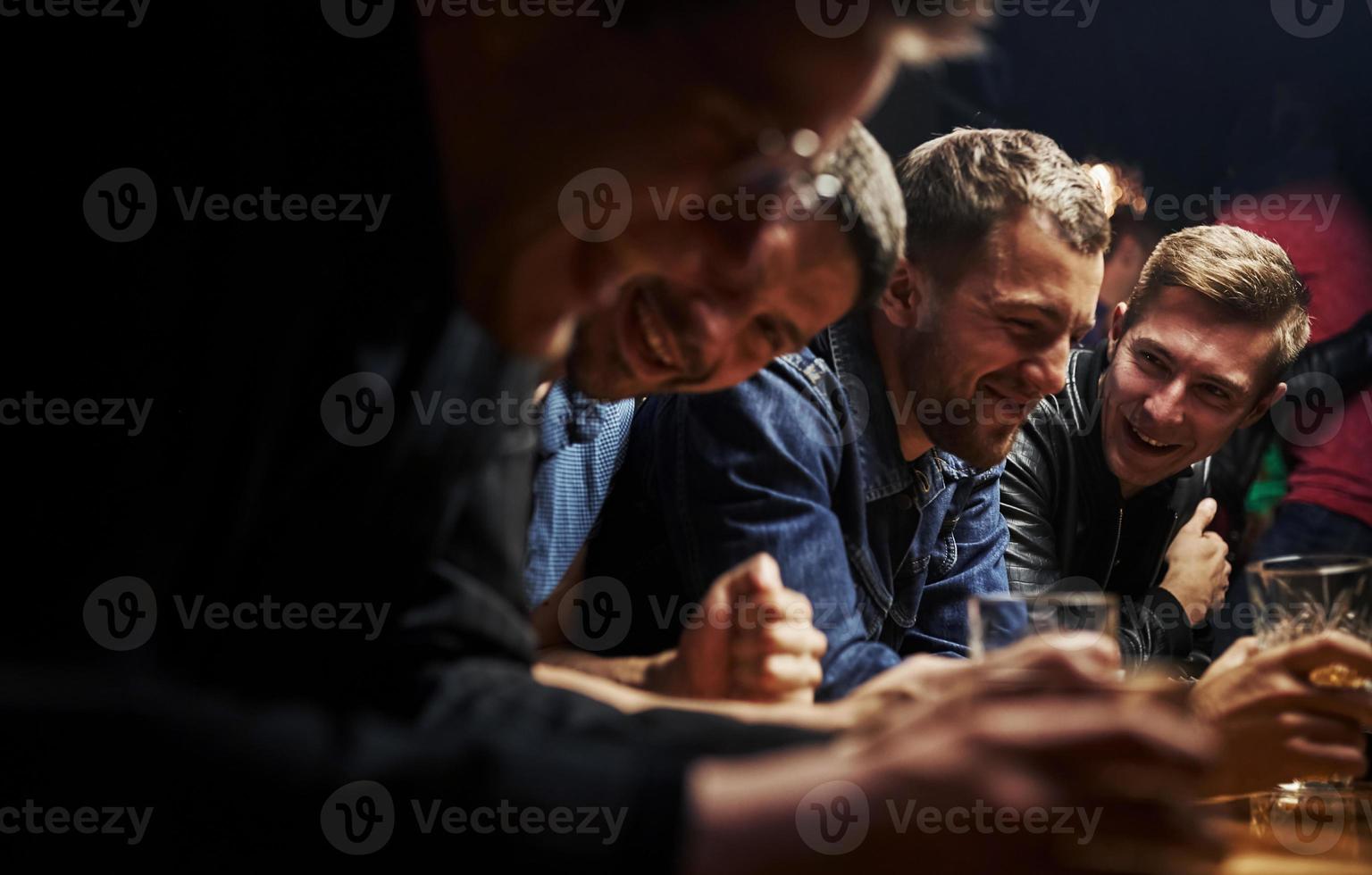 Side view. Friends resting in the pub with alcohol in hands. Having conversation photo
